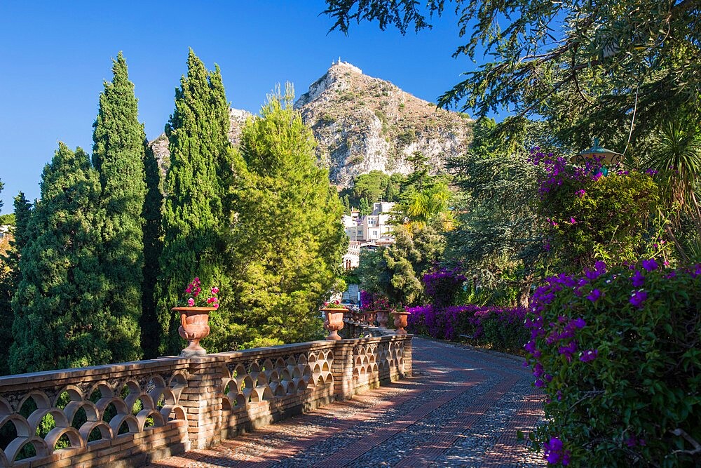 View along footpath in the gardens of the Villa Comunale, Saracen castle visible on hilltop, Taormina, Messina, Sicily, Italy, Mediterranean, Europe