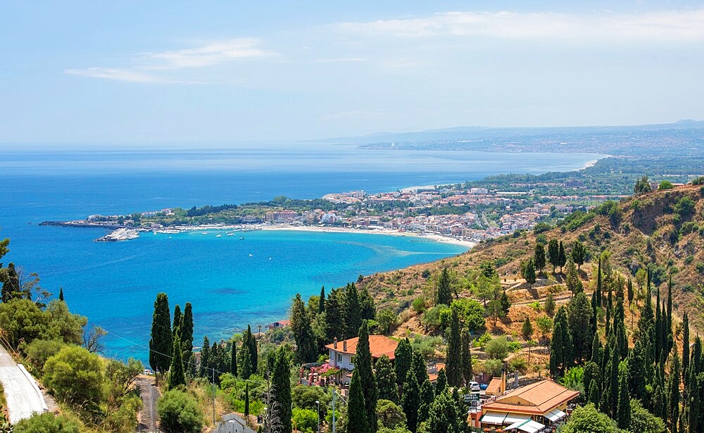 View over the turquoise waters of the Bay of Naxos to distant Giardini-Naxos, Taormina, Messina, Sicily, Italy, Mediterranean, Europe