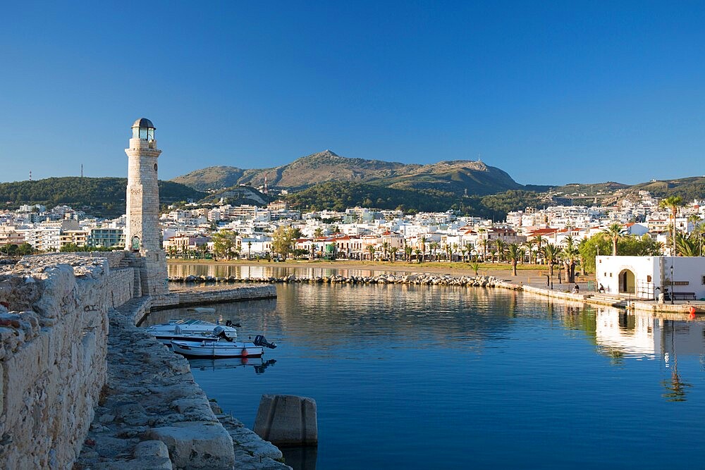 View along sea wall of the Venetian Harbour, 16th century lighthouse prominent, Rethymno (Rethymnon), Crete, Greek Islands, Greece, Europe