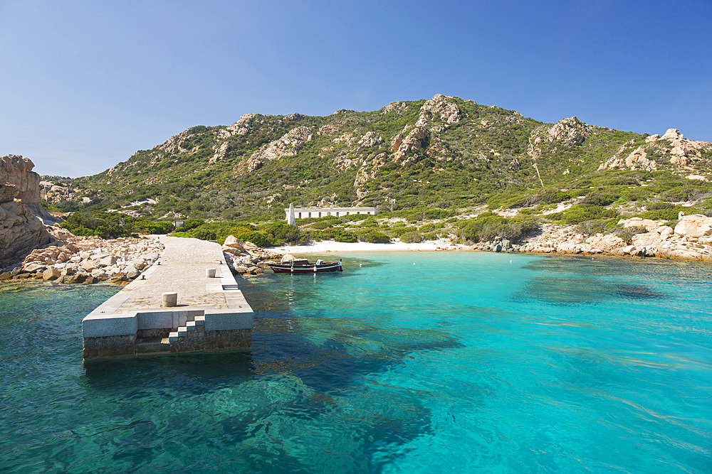 View across clear turquoise water to the fine white sands of the Spiaggia di Punta Rossa Corsara, boat jetty in foreground, Spargi Island, La Maddalena Archipelago National Park, Sassari, Sardinia, Italy, Mediterranean, Europe