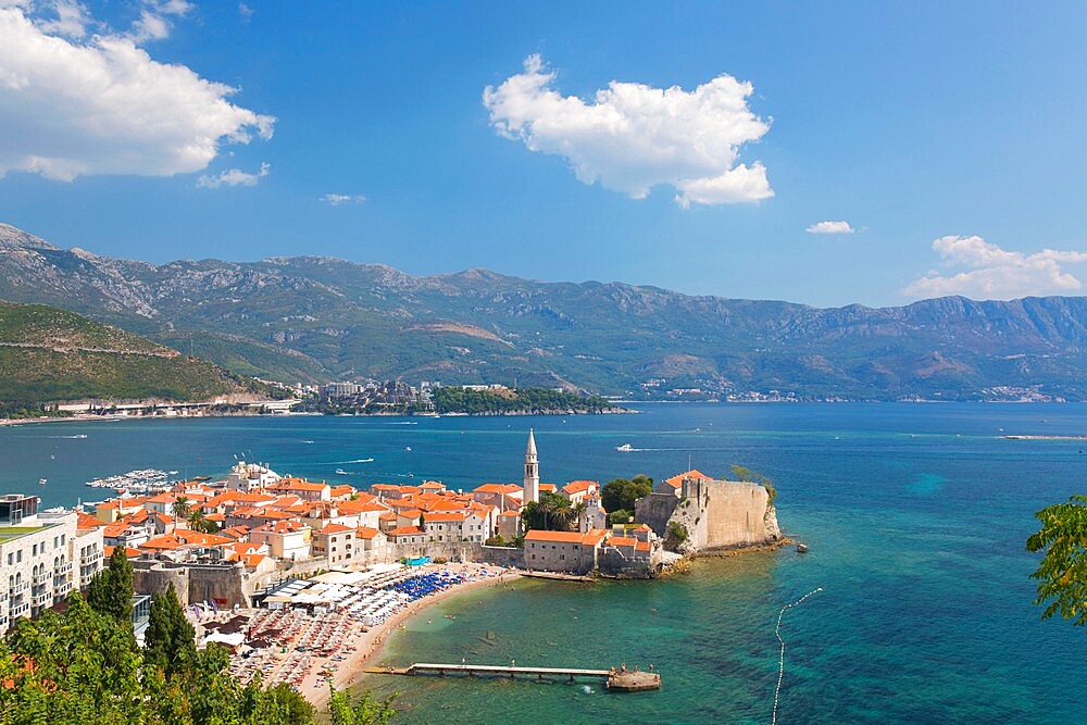 View over crowded beach to the Old Town (Stari Grad), and Budva Bay, Budva, Montenegro, Europe