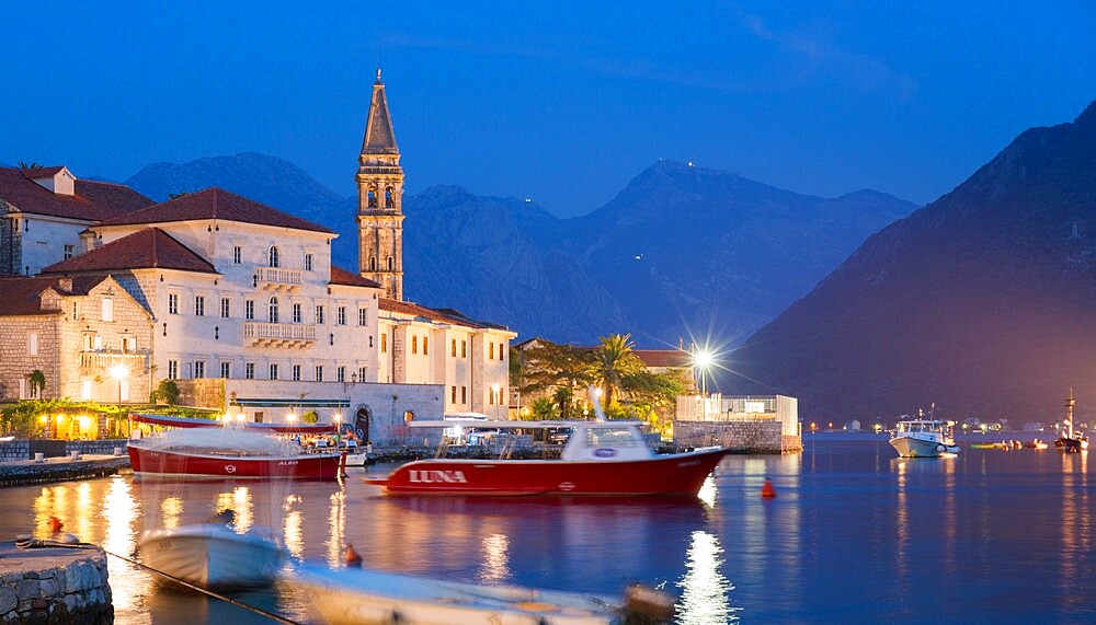 View across the illuminated harbour to waterfont mansions overlooking the Bay of Kotor, dusk, Perast, Kotor, UNESCO World Heritage Site, Montenegro, Europe