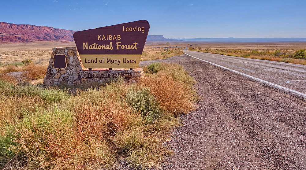 Highway US89A in Arizona looking east toward the Vermilion Cliffs National Monument with a sign on the left marking the boundary of the Kaibab National Forest.