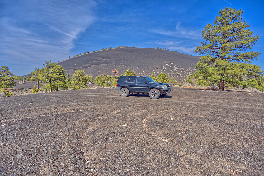 An SUV traveling near Volcanic cinder hills in Coconino National Forest, Arizona, USA