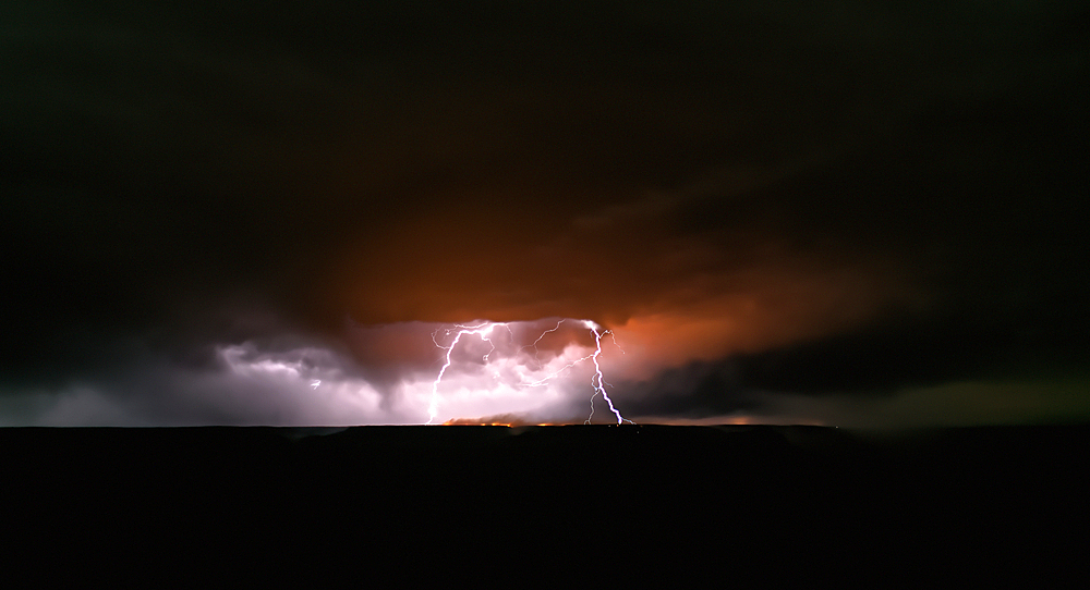 Dragon Bravo wildfire burning on the North Rim of Grand Canyon Arizona with a lightning storm. Viewed from Yavapai Point on the South Rim at night. The fire started from a lightning strike on July 4th, 2025.