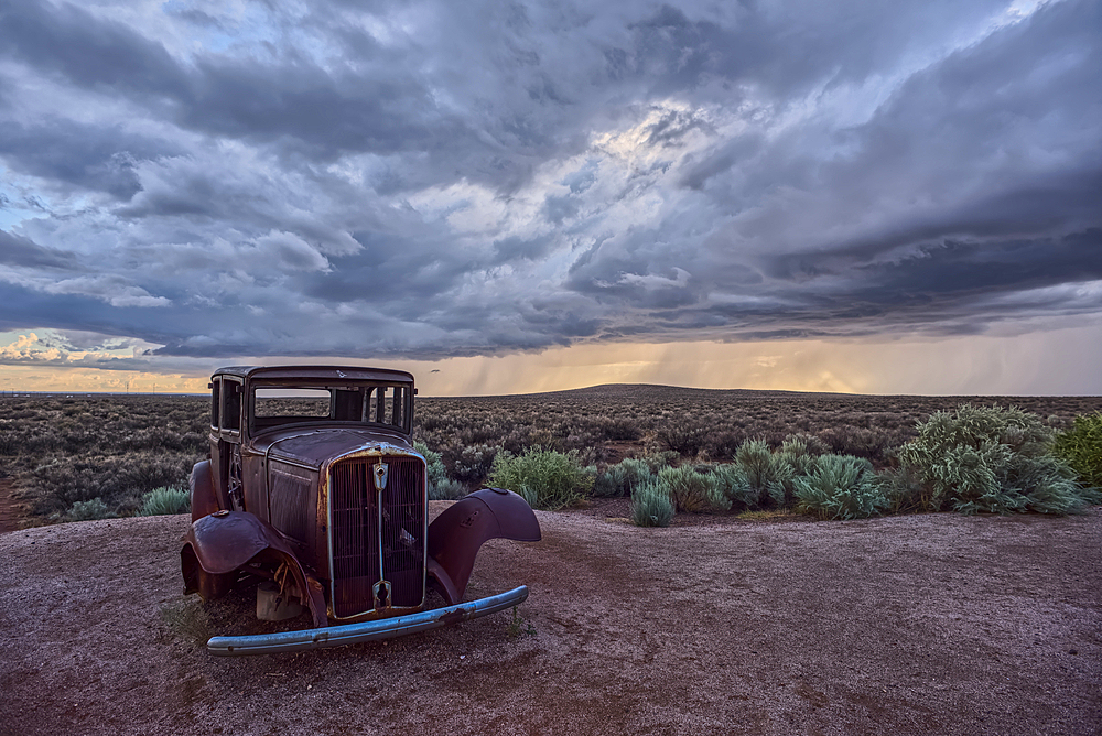 An old Model-T marking historic Route-66 in Petrified Forest National Park Arizona with an approaching storm in the background.