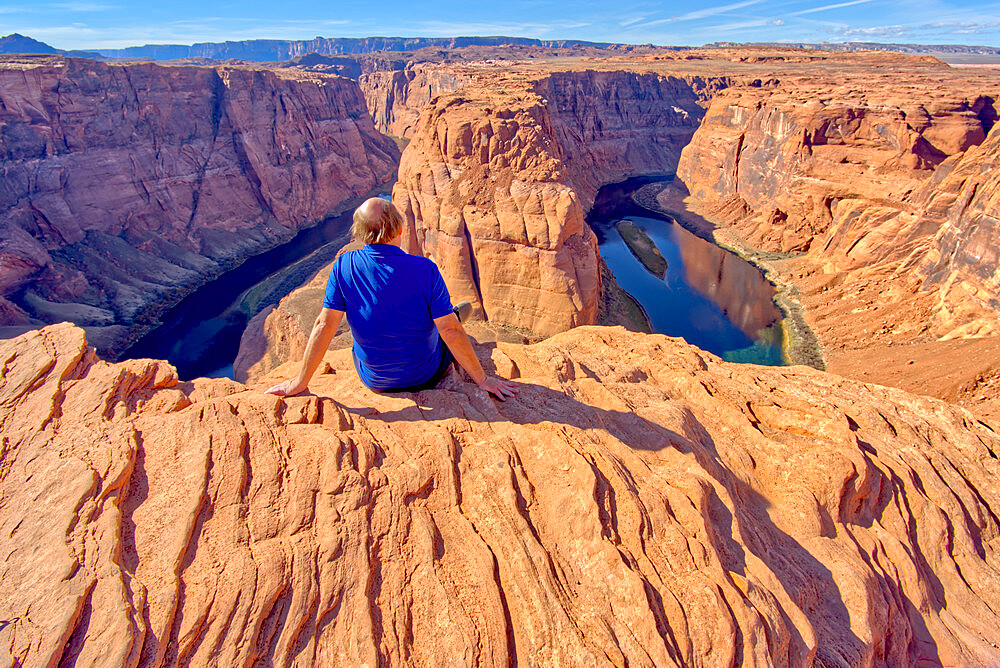 A man sitting on the edge of a cliff overlooking Horseshoe Bend near Page, Arizona, United States of America, North America