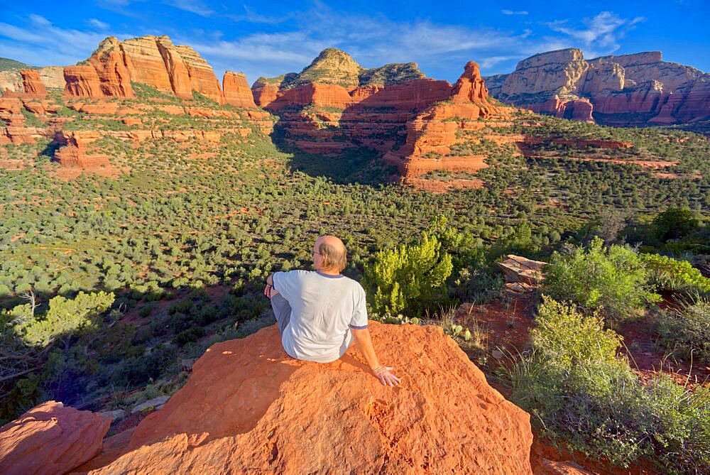 A man sitting on the top of Mescal Mountain overlooking Deadmans Pass in Sedona Arizona.