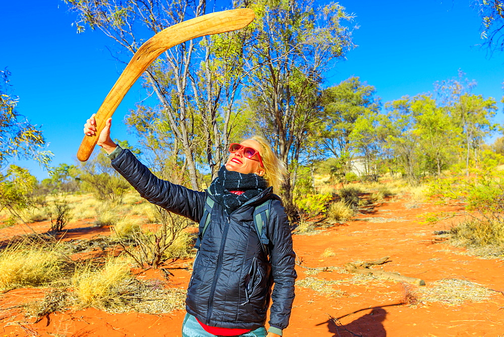 Happy tourist woman holding an aboriginal weapon of boomerang used by Luritja and Pertame people in Central Australia, Northern Territory, Australia, Pacific