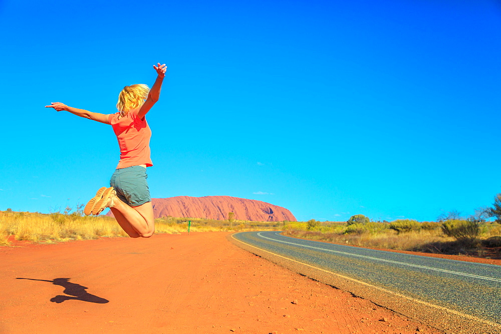 Tourist woman jumping at Uluru (Ayers Rock) in Uluru-Kata Tjuta National Park, UNESCO World Heritage Site, Northern Territory, Central Australia, Pacific