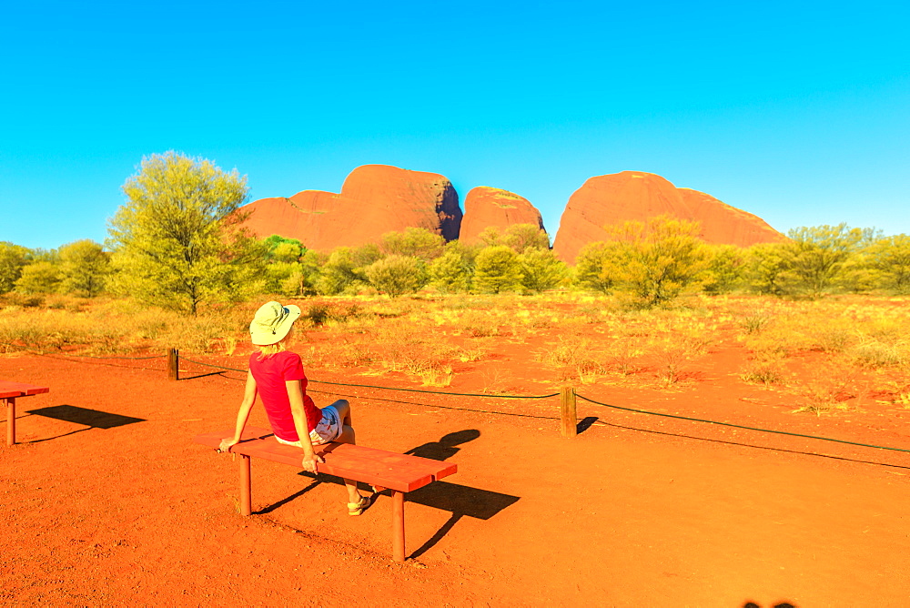 Tourist woman relaxing on a bench admiring the vibrant color of domed rock formations from Kata Tjuta Sunset viewing area, Uluru-Kata Tjuta National Park, UNESCO World Heritage Site, Northern Territory, Australia, Pacific