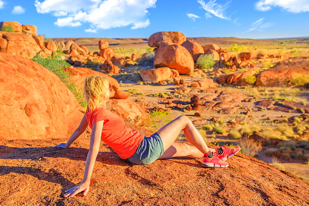 Tourist woman on Nyanjiki Lookout at sunset admiring panoramic views and vibrant colors of gigantic boulders of natural rock formations at Karlu Karlu (Devils Marbles), Northern Territory, Australia, Pacific