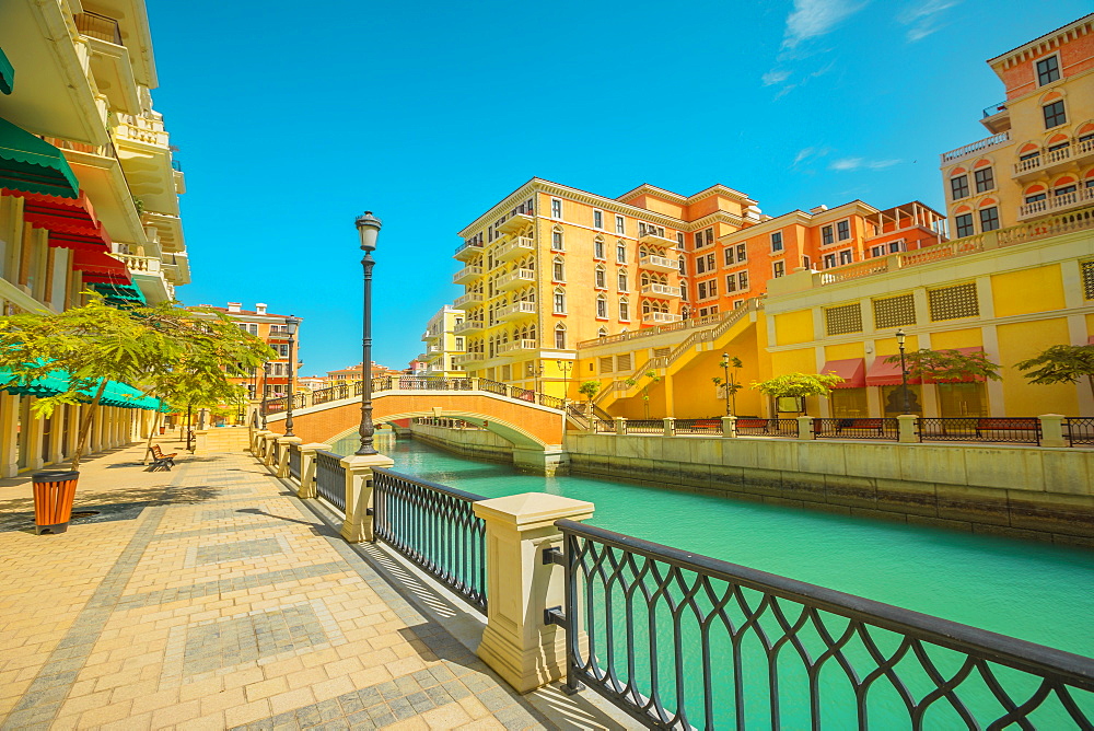 Beautiful Little Venice with canals connected by bridges in Venetian style and colourful houses in picturesque Qanat Quartier, Venice at the Pearl in sunset light, Doha, Qatar, Middle East