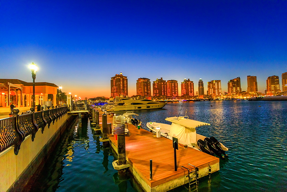 Luxurious yachts and boats docked at Porto Arabia Marina at night, The Pearl-Qatar, an artificial island icon of the city and a popular tourist destination in the Persian Gulf, Doha, Qatar, Middle East