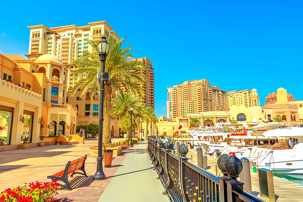 Marina corniche promenade in Porto Arabia at the Pearl-Qatar, with residential towers and luxury boats and yachts in Persian Gulf, Doha, Qatar, Middle East