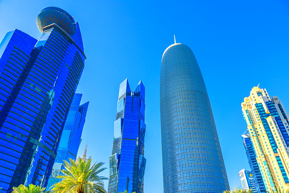 Low angle view of Woqod Tower and Alfardan Towers in West Bay area, modern glassed skyscrapers in Downtown Doha, Qatar, Middle East