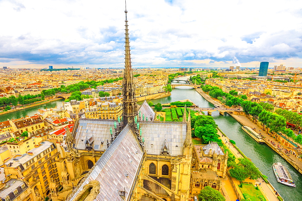 Detail of the spire of Notre Dame Cathedral (Our Lady of Paris) with statues, and city skyline, Paris, France, Europe