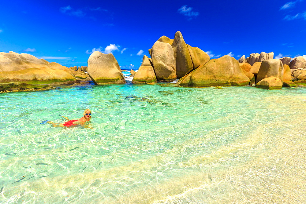 Attractive woman in bikini, in crystal water of natural swimming pool at secret beach, Anse Marron, La Digue, Seychelles, Indian Ocean, Africa