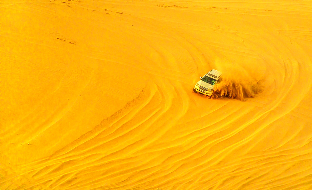 Desert safari adventure in 4x4 vehicle bashing side to side through the desert dunes at sunset in Qatar and Saudi Arabia, Qatar, Middle East