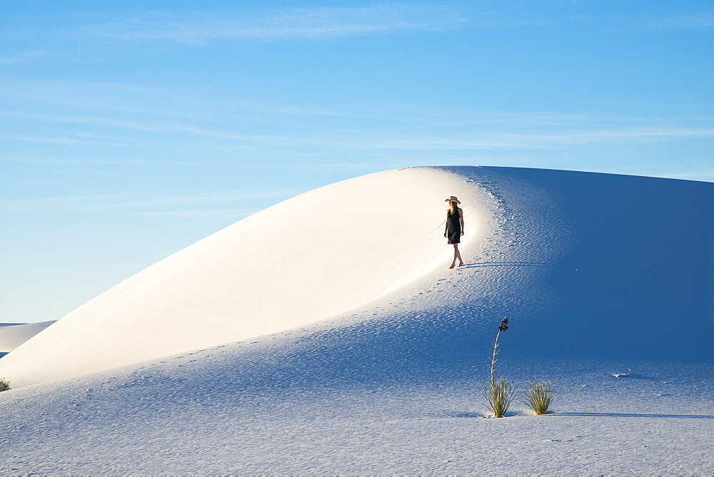 A woman strolls along the ridge of a pure white sand dune in White Sands National Park, New Mexico, United States of America, North America