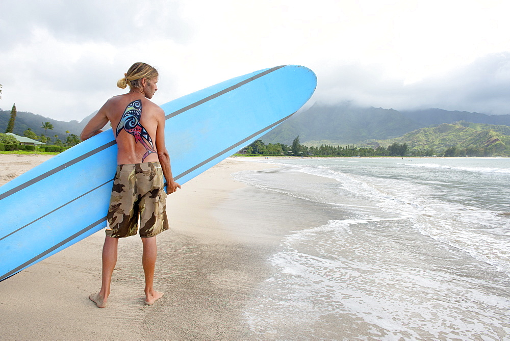 Surfer in Hanalei Bay, with a shark painted on his back, Kauai, Hawaii, United States of America, North America