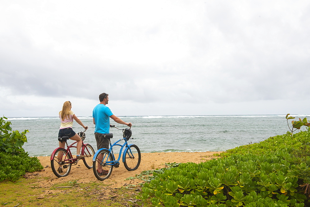 Couple with bicycles looking out at the ocean on Kauai near Kapaa, Hawaii, United States of America, North America