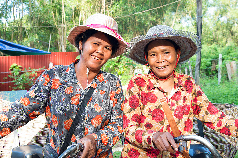 Two local women with their bicycles smiling together in Siem Reap, Cambodia, Indochina, Southeast Asia, Asia