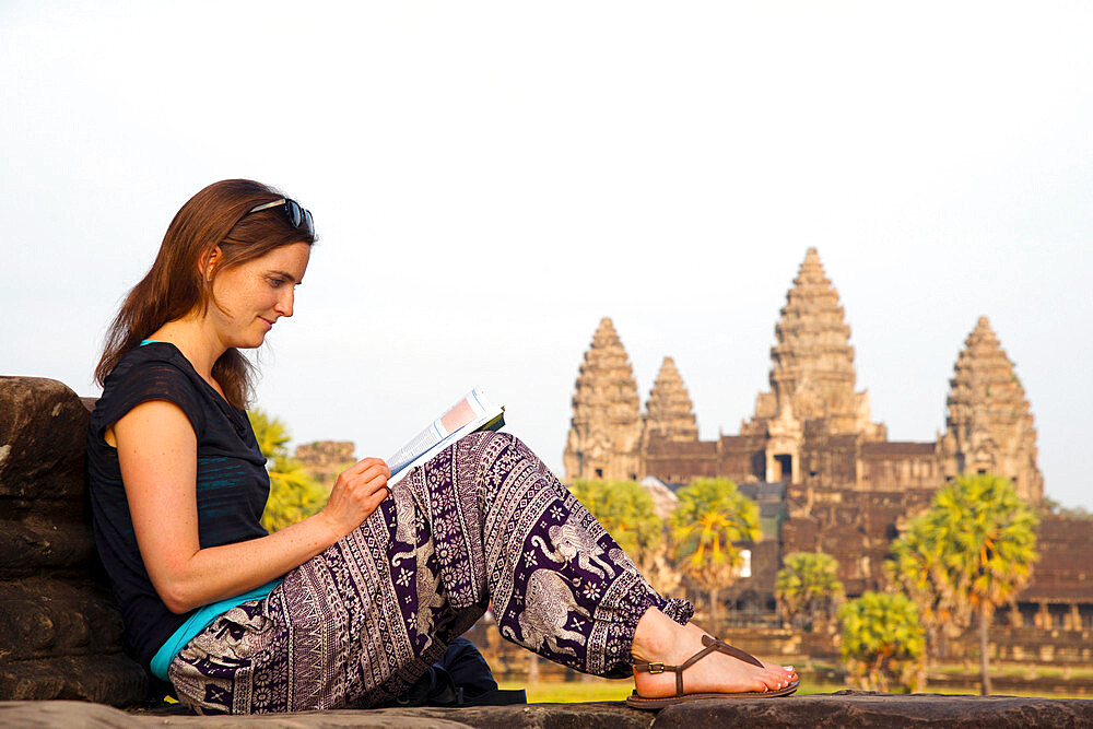 Female tourist reading a guidebook at Angkor Wat, UNESCO World Heritage Site, Siem Reap, Cambodia, Indochina, Southeast Asia, Asia