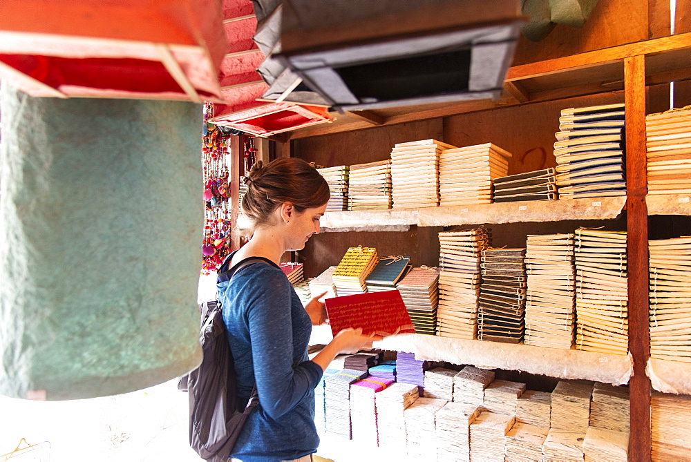 A tourist browses notebooks at a paper shop in Luang Prabang, Laos, Indochina, Southeast Asia, Asia