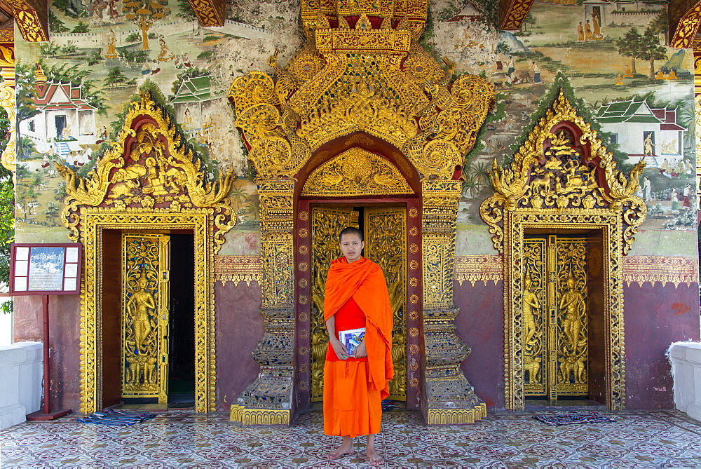 A Buddhist monk in saffron robes standing at the Royal Palace, Luang Prabang, Laos, Indochina, Southeast Asia, Asia