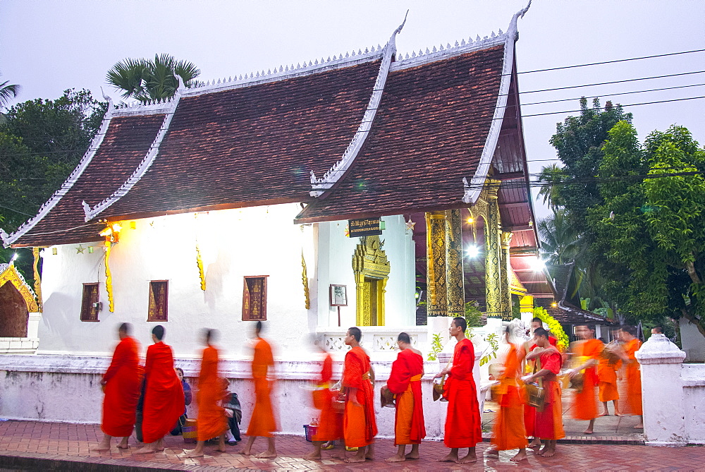 Buddhist monks receive rice from locals during an early morning daily ritual known as Sai Bat (morning alms) in Luang Prabang, Laos, Indochina, Southeast Asia, Asia