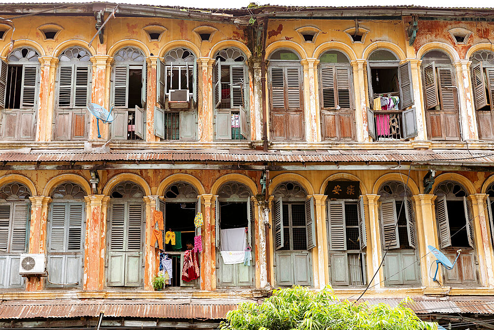 The first and second floors of an old colonial apartment building in Chinatown, showing archways and wooden doors, Yangon (Rangoon), Myanmar (Burma), Asia