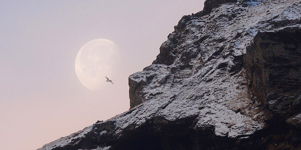 Moon setting behind snow covered mountains, Iceland, Polar Regions