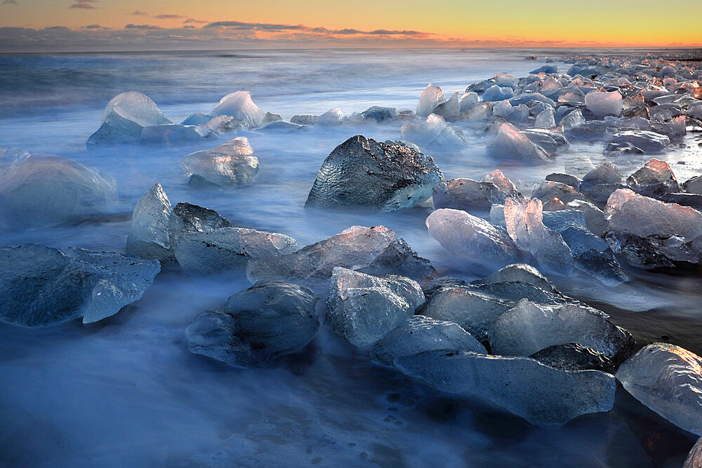 Pieces of glacial ice over black sand being washed by waves, Iceland, Polar Regions