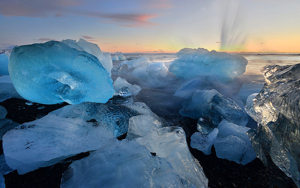 Pieces of glacial ice over black sand being washed by waves, Iceland, Polar Regions