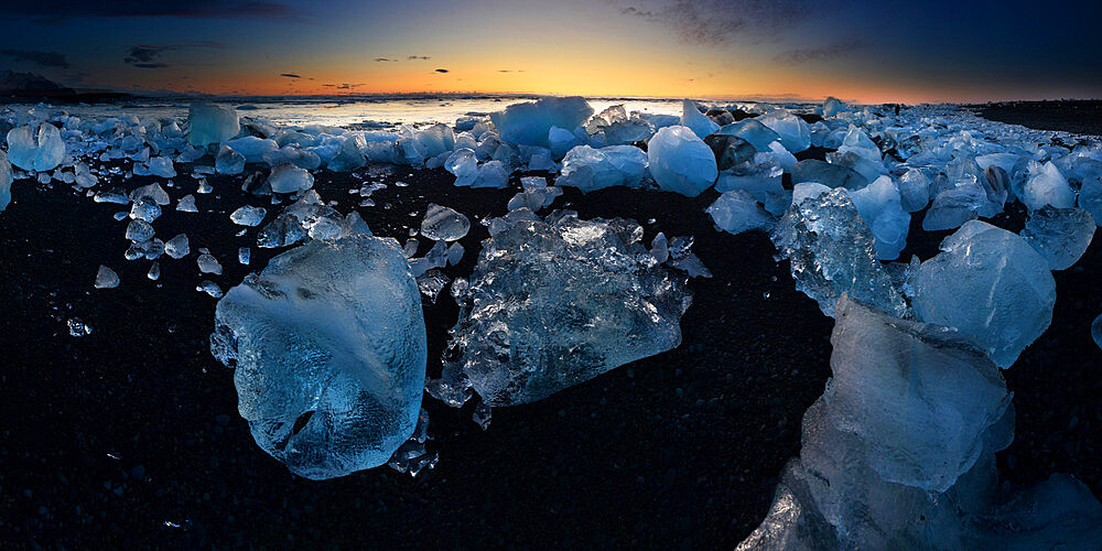 Pieces of glacial ice over black sand being washed by waves, Iceland, Polar Regions