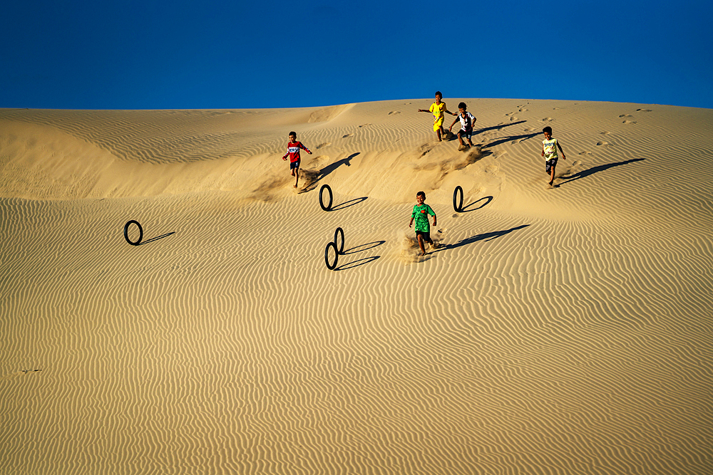 Children rolling tyres as hoops down the Nam Cuong sand hill in Ninh Thuan, Vietnam, Indochina, Southeast Asia, Asia