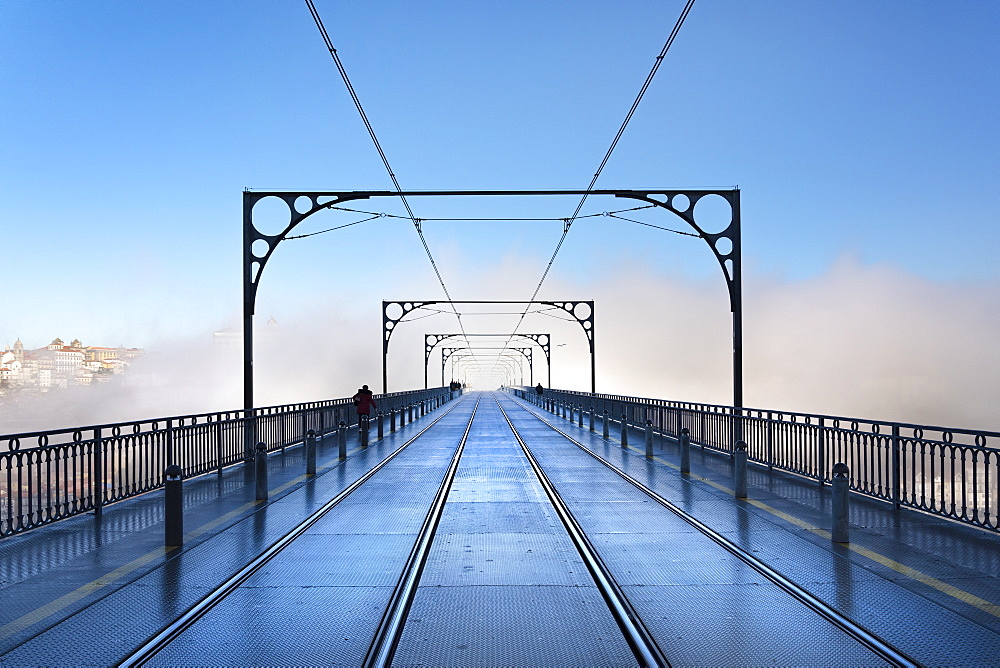 Tram tracks in the early morning mist running over Dom Luis I Bridge in Porto, Portugal, Europe