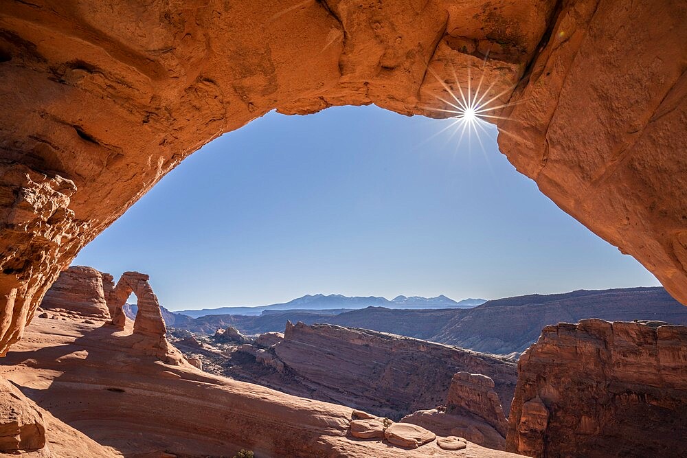 View of Delicate Arch through Frame Arch with sunburst, Arches National Park, Utah, United States of America, North America