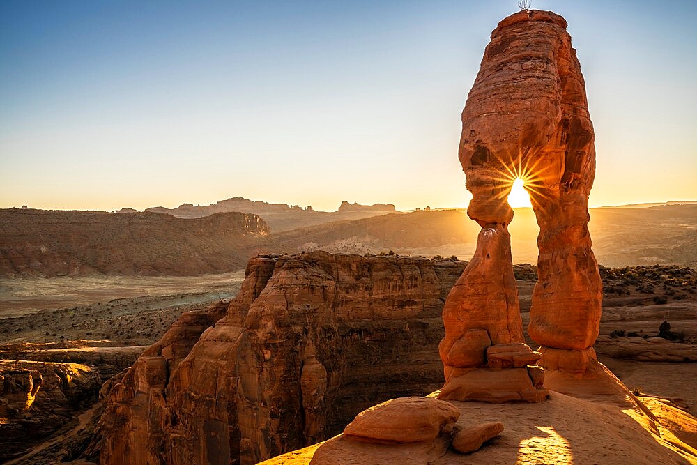 Setting sun through Delicate Arch with sunburst, Arches National Park, Utah, United States of America, North America