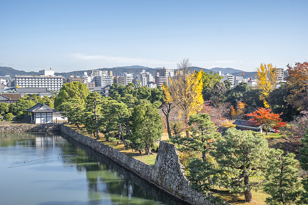 Nijo Castle garden and moat in autumn with the modern city in the background, Kyoto, Honshu, Japan, Asia