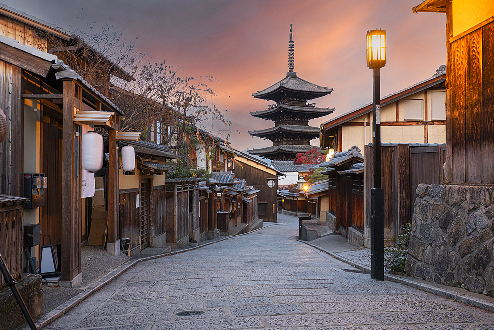 A narrow street lined with old buildings leading towards the Hokan-ji Gojunoto pagoda peeking out in the distance against the sunrise sky, Kyoto, Honshu, Japan, Asia