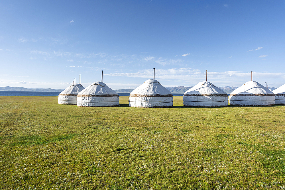 Traditional yurts dotting the picturesque landscapes near Song-Kol Lake in Kyrgyzstan during bright daylight