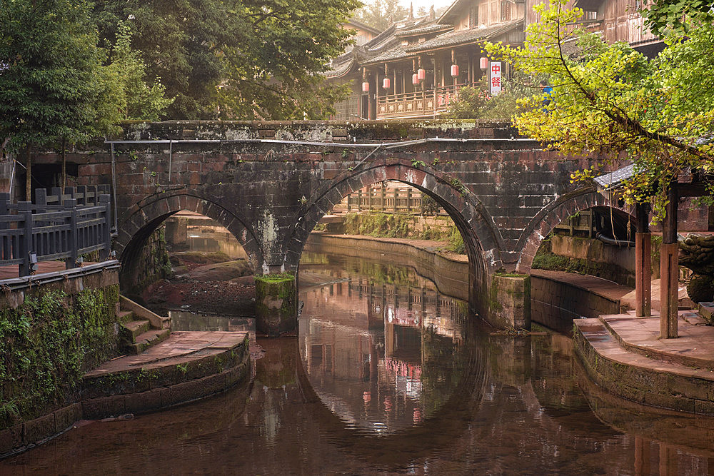 A three-arched stone bridge and his reflection in Shangli Town at dawn