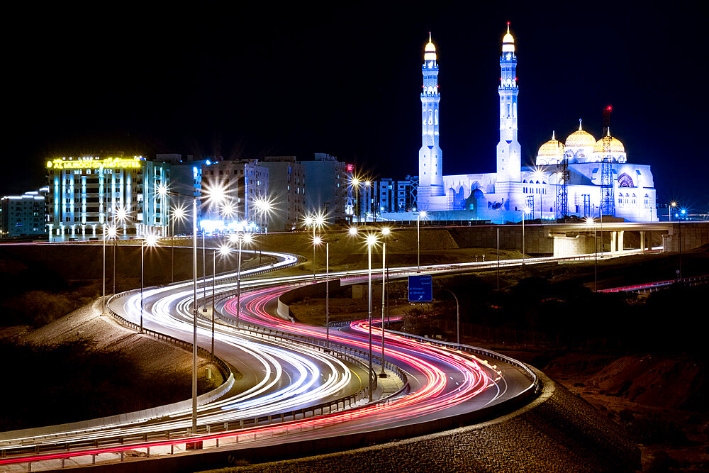 Long exposure cityscape night shot with a blue mosque and a street with car trails, Muscat, Oman, Middle East