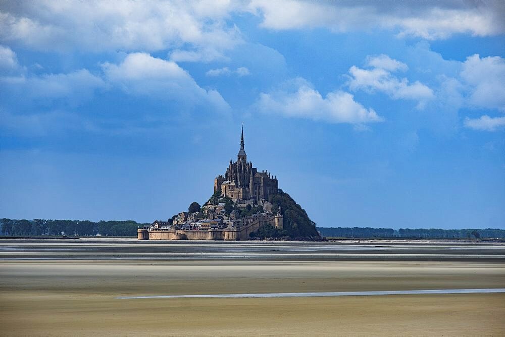 Le Mont Saint Michel with low tide in a sunny day with some white clouds, Normandy, France