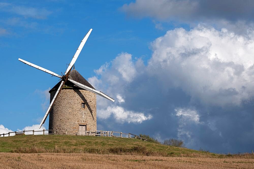 Windmill on top of a hill with a blue sky with white clouds, Normandy, France