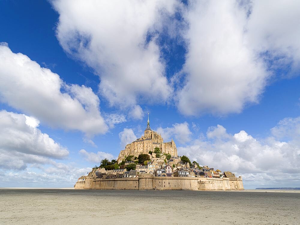 Mont Saint Michel in a low tide day with a blue sky with clouds, Normandy, France