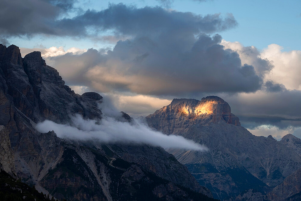 Sunset with clouds on Croda Rossa d'Ampezzo in the Dolomites with a single beam of light on the rock, Dolomites, Italy, Europe