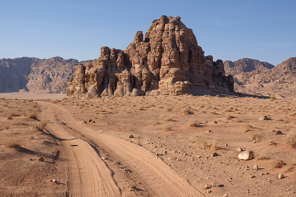 Off-road vehicle tracks in the sand of Wadi Rum leading to a rocky mountain, Wadi Rum, Jordan, Middle East